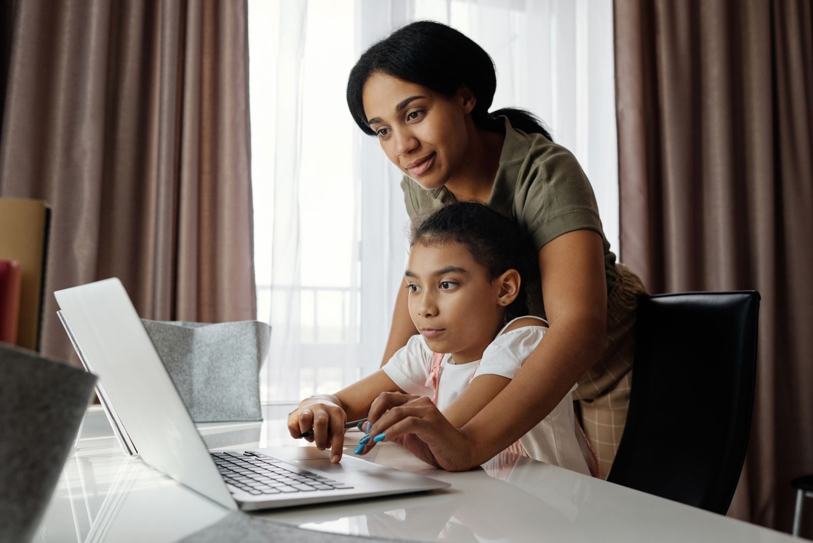 A parent and learner studying together at a laptop in a home setting